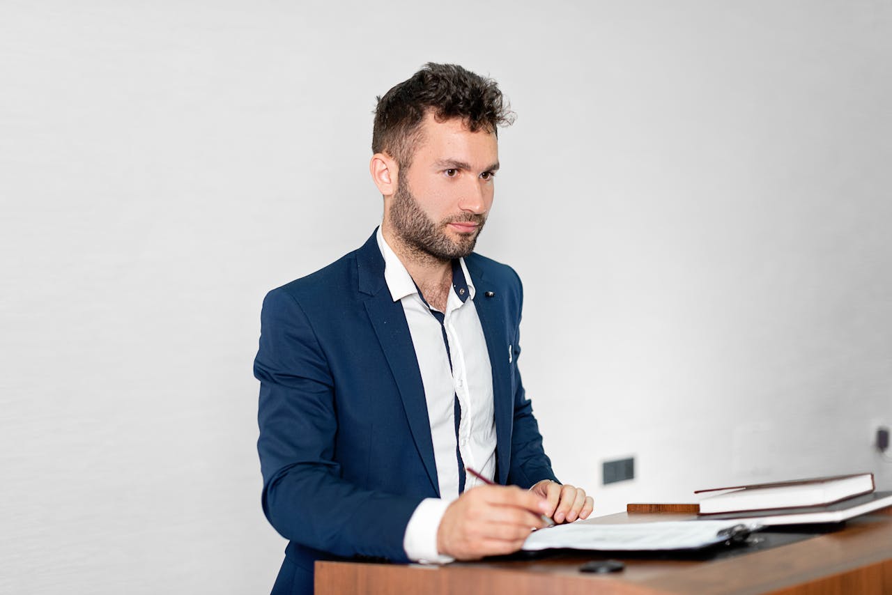 Confident businessman in a blazer presenting at a podium indoors.